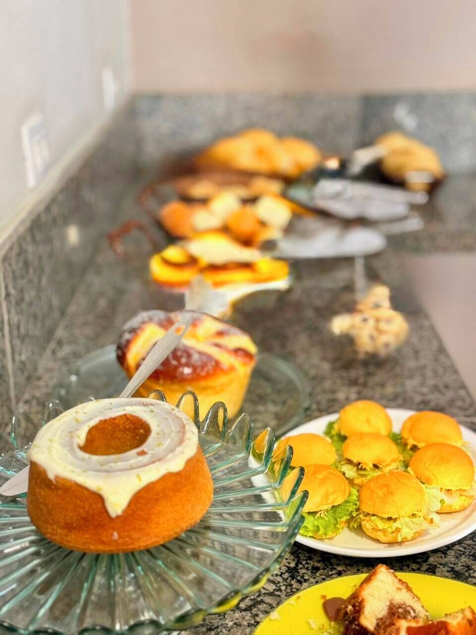 Una mesa de buffet con diversas opciones de comida, incluyendo un pastel, hamburguesas y un plato con un sándwich.