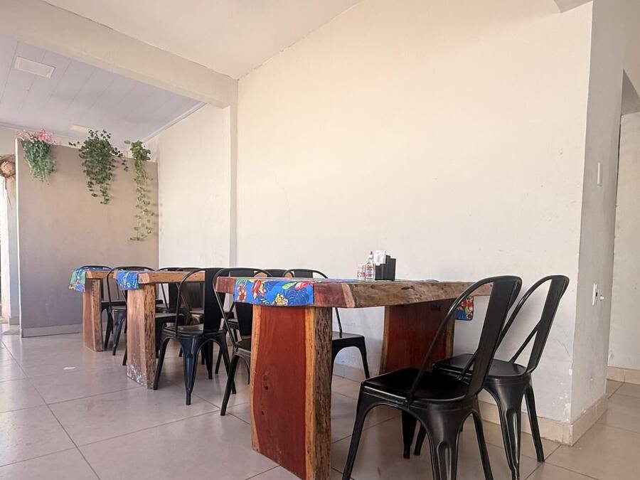 A dining area with a wooden table and black chairs, a ceiling fan, and hanging plants.