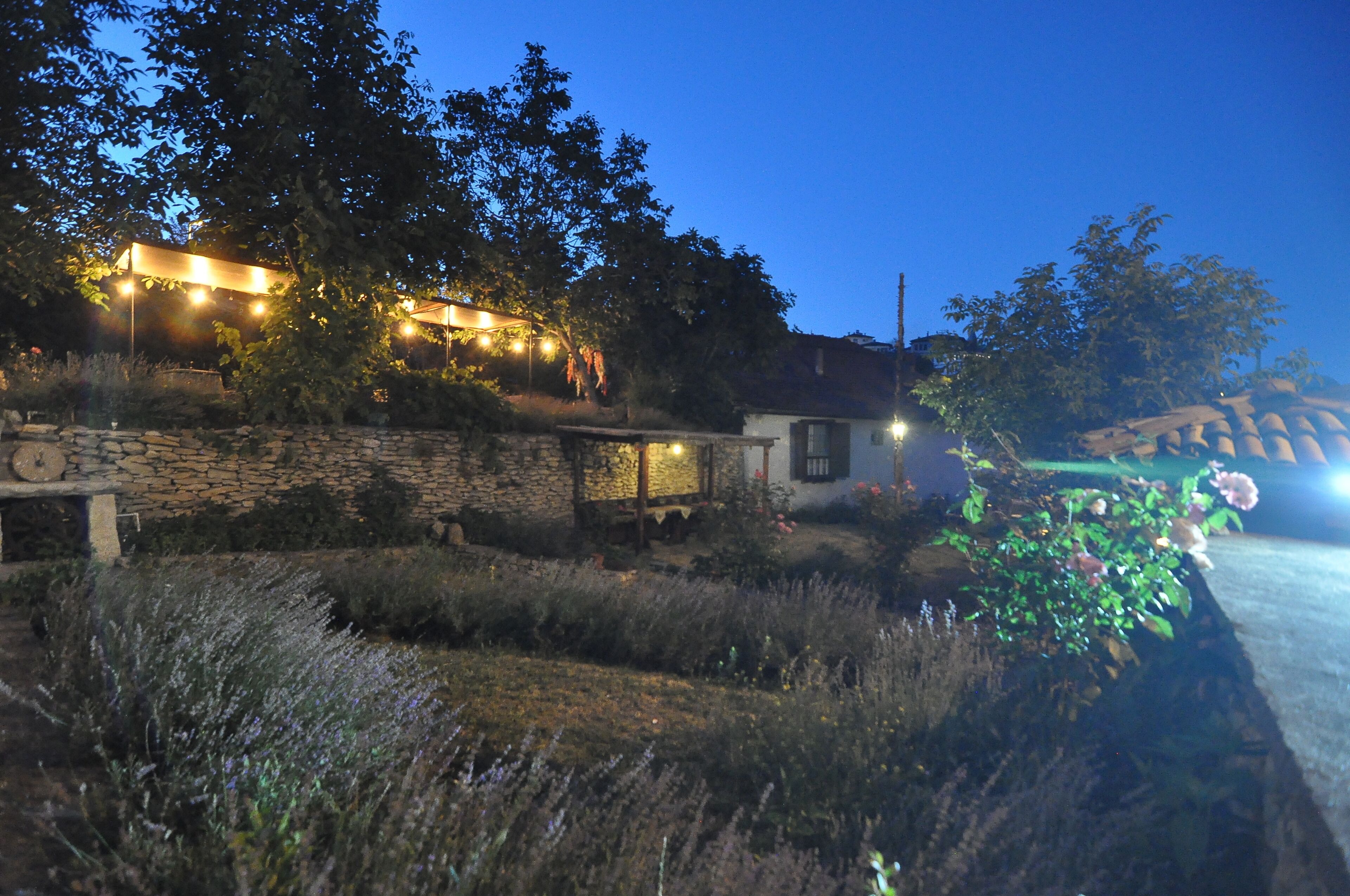 A stone wall with a small building, possibly a guesthouse, and a garden with various plants and flowers.