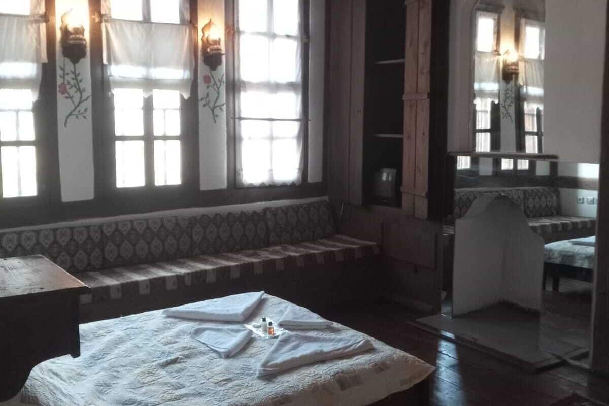 Quarto com cama grande, um banquinho e um espelho.