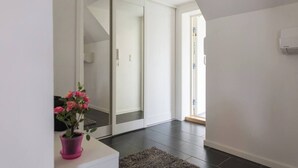 A modern interior with a sliding glass door leading to a balcony, a potted plant, and a white wall with a thermostat. - Penthouse by Brosundet, Free Parking Space (Ålesund)