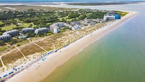 Eine Vogelperspektive zeigt ein Küstenhotel mit mehreren Gebäuden, einem Sandstrand und freiem Blick auf den Ozean.