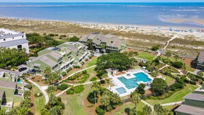 Ein Küstenresort mit mehrstöckigen Gebäuden, einem zentral gelegenen Schwimmbecken und Blick auf den Strand.