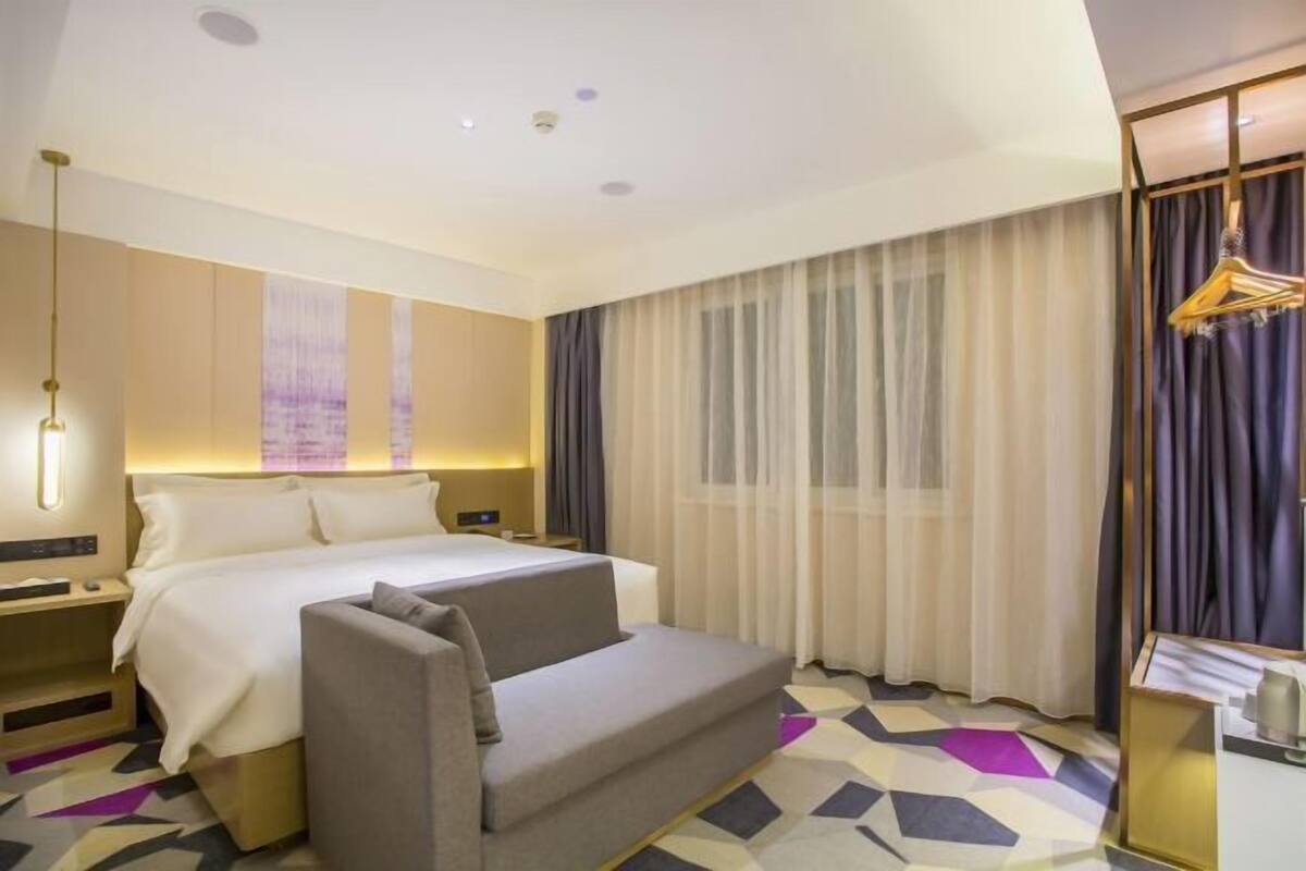 A hotel room with a bed, a sofa, a desk, a chair, and a wardrobe.