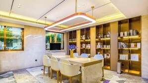 A modern hotel lobby with a marble floor, a central island with seating, and a large bookshelf filled with books and decorative items. - Lavande Hotel (Beijing Guomao) (Beijing)