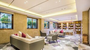 A modern hotel lobby with a sofa, armchairs, and a bookshelf. - Lavande Hotel (Beijing Guomao) (Beijing)