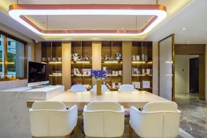 A modern dining area with a long table, white chairs, and a central vase. - Lavande Hotel (Beijing Guomao) (Beijing)