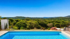 A swimming pool with a view of green hills and a clear sky.