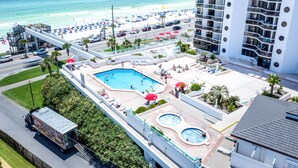 Ein Hotel mit Poolbereich, Blick auf den Strand und einem Parkplatz.