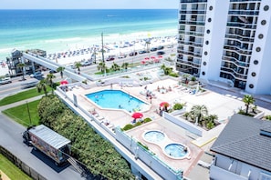A hotel with a pool, beach view, and a tall building in the background.