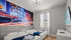 A hotel room with two beds, a desk, and a large window with blinds.