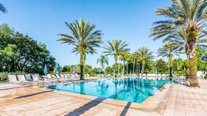 A swimming pool with lounge chairs and palm trees.
