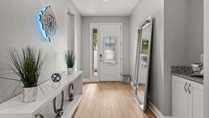 A hallway with a white door, a mirror, and a countertop with a toaster.
