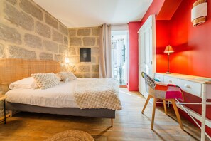Relax in this serene bedroom with a large bed, wooden desk, and a window offering a view of the outside.