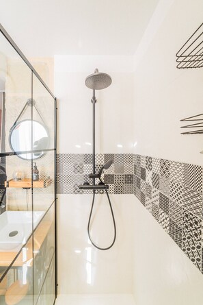 Bathroom features a glass-enclosed shower, handheld showerheads, and a large mirror.