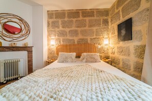 Restful retreat with a large bed, stone wall, and a red mirror above.