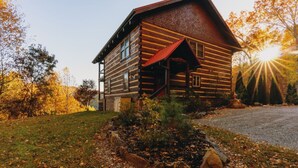 A log cabin with a porch, surrounded by a grassy area with a - Heavens Ridge-3-bedroom Pet Friendly Luxury Log Cabin Rental, Mountain Views, 30 Minutes to Great Smokey Mountains, High Speed Internet, 3 Decks, Hot Tub in Nantahala NC (Topton)