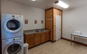 A laundry room with a front-loading washing machine, a sink, wooden cabinets, and a door. - Heavens Ridge-3-bedroom Pet Friendly Luxury Log Cabin Rental, Mountain Views, 30 Minutes to Great Smokey Mountains, High Speed Internet, 3 Decks, Hot Tub in Nantahala NC (Topton)