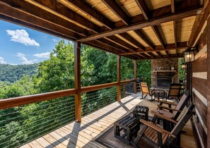 A wooden deck with outdoor seating and a stone fireplace. - Heavens Ridge-3-bedroom Pet Friendly Luxury Log Cabin Rental, Mountain Views, 30 Minutes to Great Smokey Mountains, High Speed Internet, 3 Decks, Hot Tub in Nantahala NC (Topton)