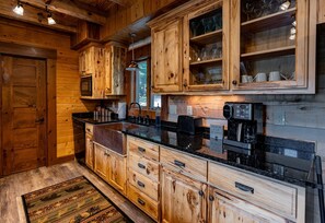 A wooden kitchen with a built-in microwave, a coffee machine, and a sign that reads 'Brew Me A Cup Of Happy.'