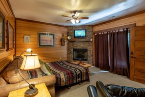A cozy room with a fireplace, a television, a sofa, and a chair.