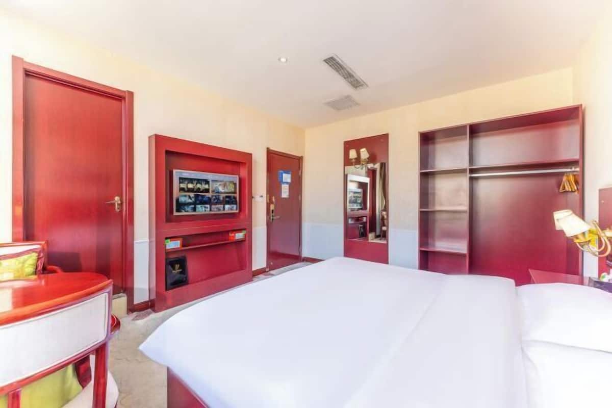 A hotel room with a bed, a desk, a TV, a wardrobe, and a mirror.