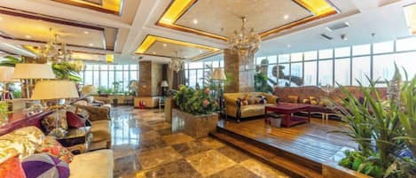 A spacious lobby with a checkered floor, plush seating, and large windows.