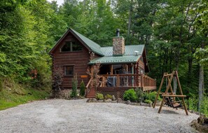 A cabin with a stone chimney, wooden deck, and a gravel driveway. - Hawk's Landing-Private Luxury Log Cabin Rental, Mountain Views, High Speed Internet, Hot Tub - 15 minutes from the NOC! (Topton)