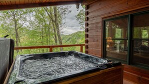 A hot tub on a wooden deck with a view of a forested hillside. - Hawk's Landing-Private Luxury Log Cabin Rental, Mountain Views, High Speed Internet, Hot Tub - 15 minutes from the NOC! (Topton)