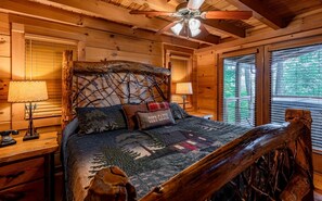 A cozy cabin room with a wooden headboard, a bed with a quilt, two bedside lamps, and a ceiling fan. - Hawk's Landing-Private Luxury Log Cabin Rental, Mountain Views, High Speed Internet, Hot Tub - 15 minutes from the NOC! (Topton)