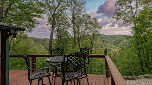 A wooden deck with metal chairs and a table, overlooking a forested valley. - Hawk's Landing-Private Luxury Log Cabin Rental, Mountain Views, High Speed Internet, Hot Tub - 15 minutes from the NOC! (Topton)