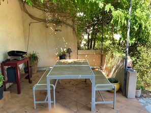 Una terrazza con tavolo e sedie, un piccolo tavolino con un altoparlante e piante in vaso.