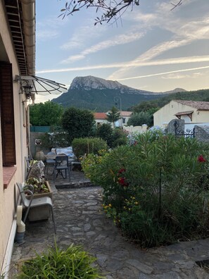 A courtyard with a stone pathway, outdoor furniture, and a mountain in the background.