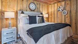 A wooden-paneled bedroom with a bed, two bedside tables, and decorative wall plates.