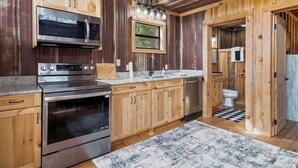 A modern kitchen with stainless steel appliances, wooden cabinets, and a large window.