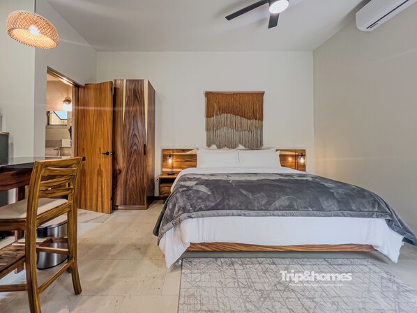 Un dormitorio con cama, armario de madera, escritorio, silla y dos lámparas de noche.