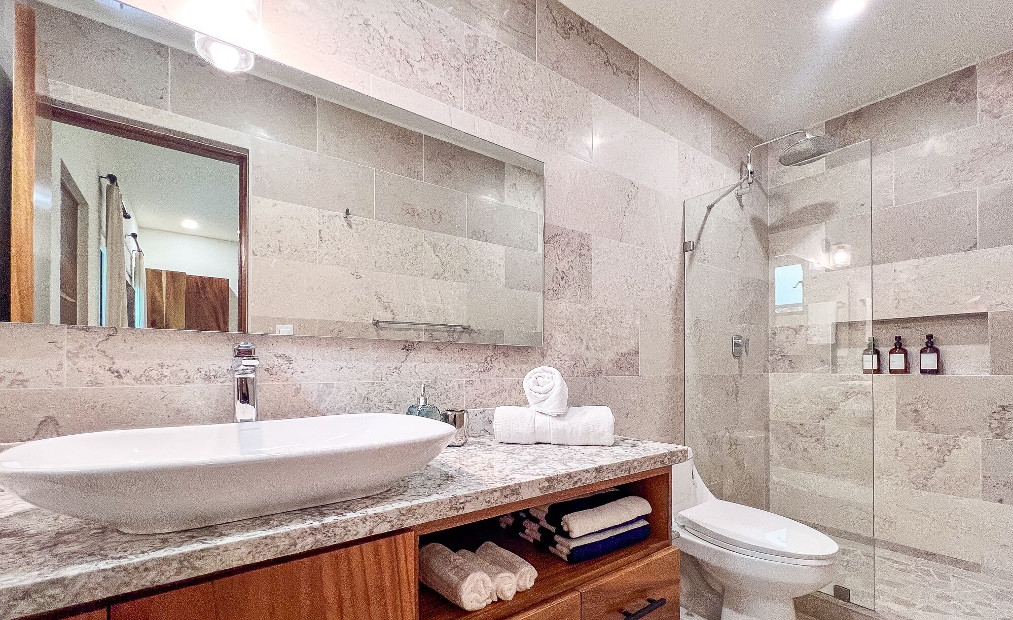 A bathroom with a marble sink, a toilet, and a shower.