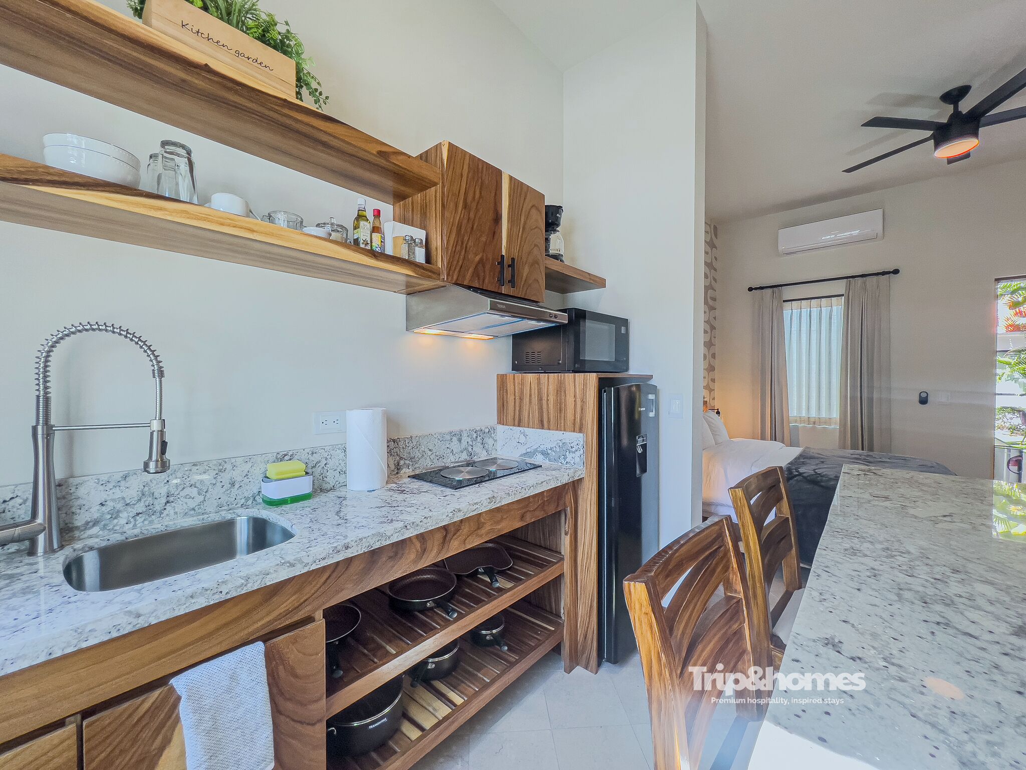 A modern kitchen with wooden shelves, a built-in microwave, and a stainless steel refrigerator.