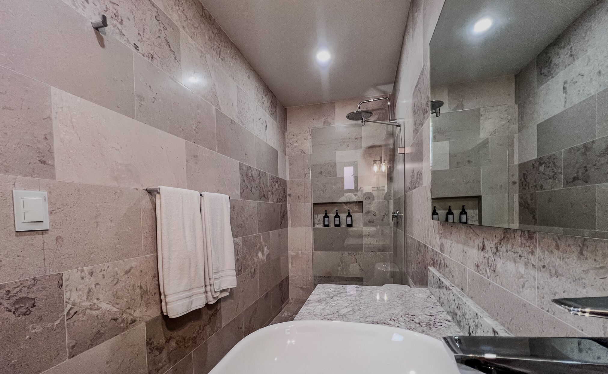 A modern bathroom with a large mirror, a bathtub, and a shower area.
