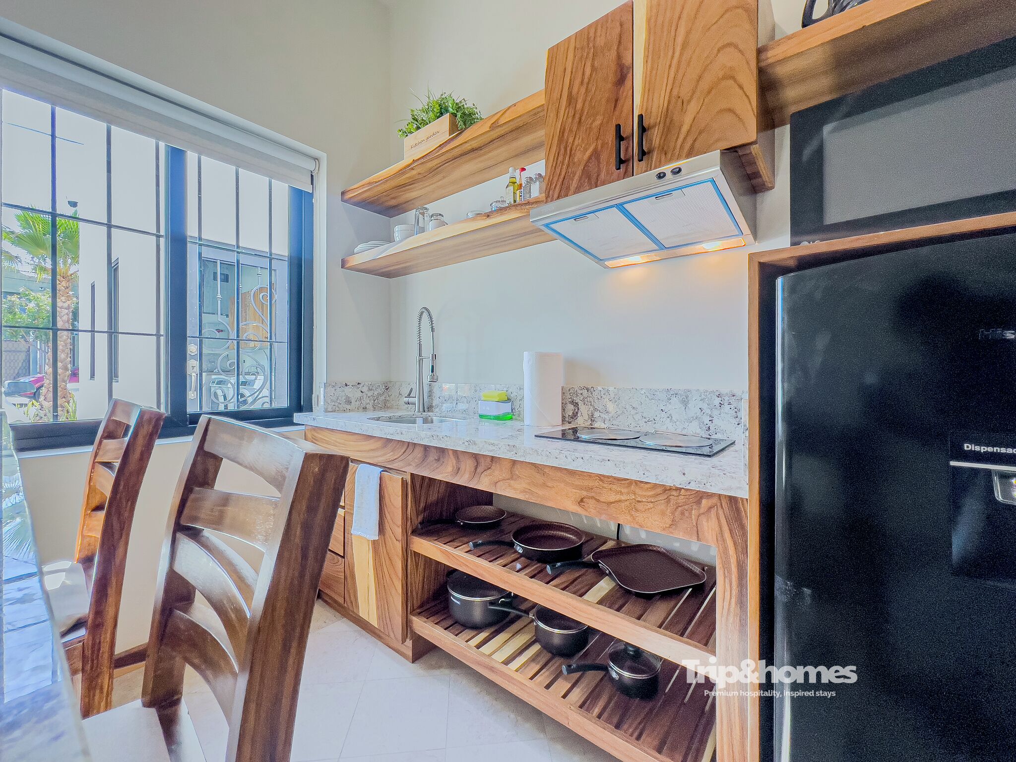 A kitchen with wooden cabinetry, a built-in stove, and a window with a view of the outside.