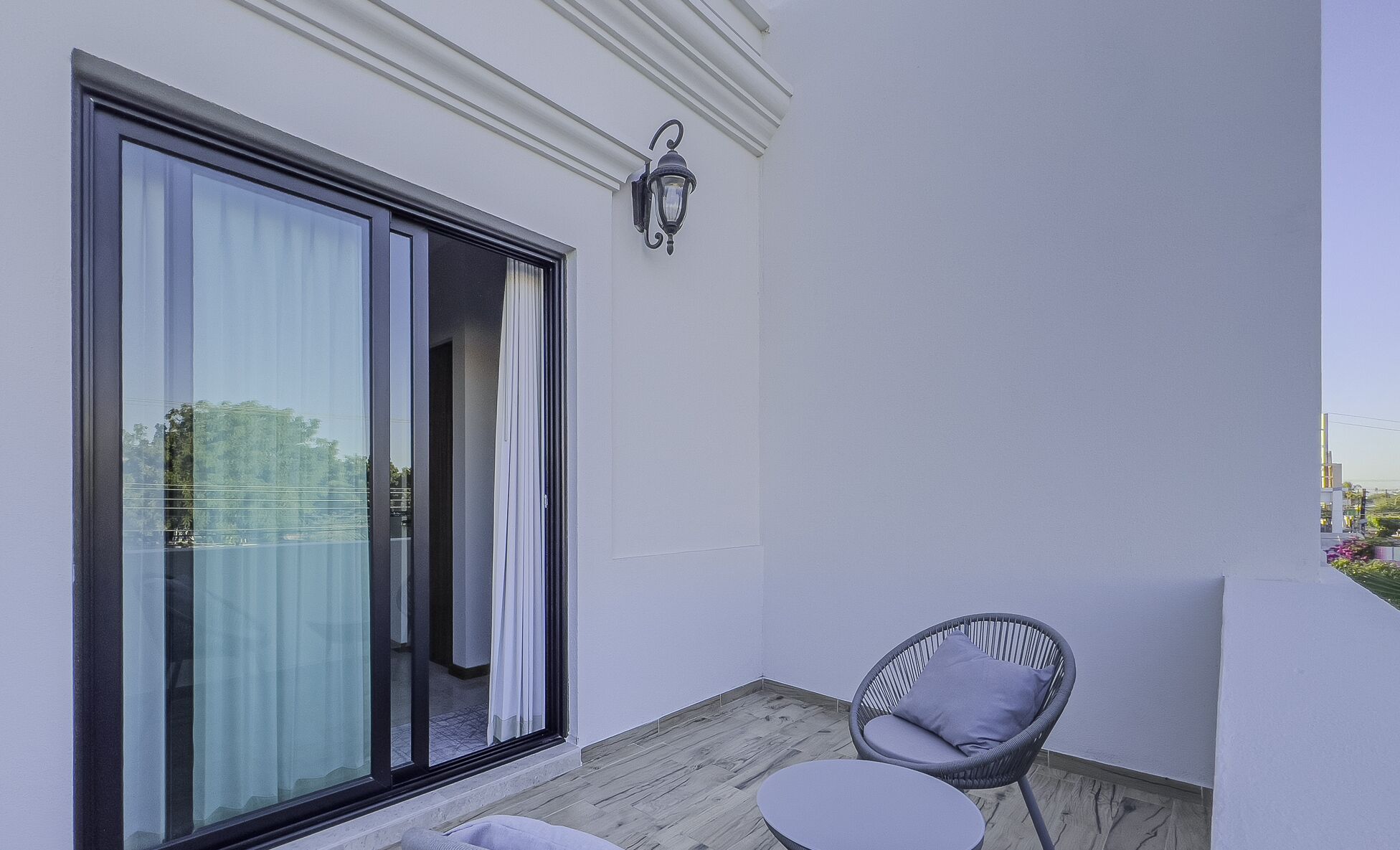 A balcony with a sliding glass door, a wicker chair, and a small round table.