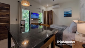 Una cocina moderna con encimera negra, armarios de madera e iluminación colgante.
