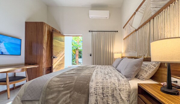 Ein Schlafzimmer mit Bett, Schreibtisch, Fernseher und einem Fenster mit Vorhängen.