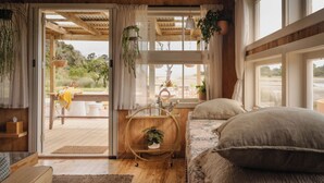 A cozy bedroom with a bed, a wooden floor, and a view of the outdoors.