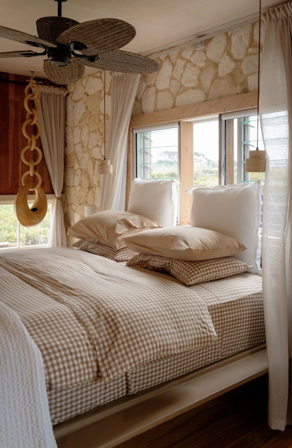 Een slaapkamer met een bed, een plafondventilator, een stenen muur en een raam.