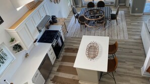 Een moderne keuken met witte kasten, een centraal eiland en een eethoek met geruit tafelkleed.