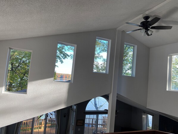 A room with a sloped ceiling, multiple windows, and a ceiling fan. - Eau Pleine Lake Retreat (Mosinee)