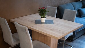 Ein moderner Essbereich mit einem Holztisch, weißen Stühlen und einem Blumentopf.