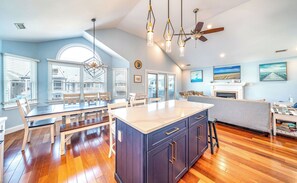Una cocina amplia con una isla grande, suelo de madera y ventilador de techo.