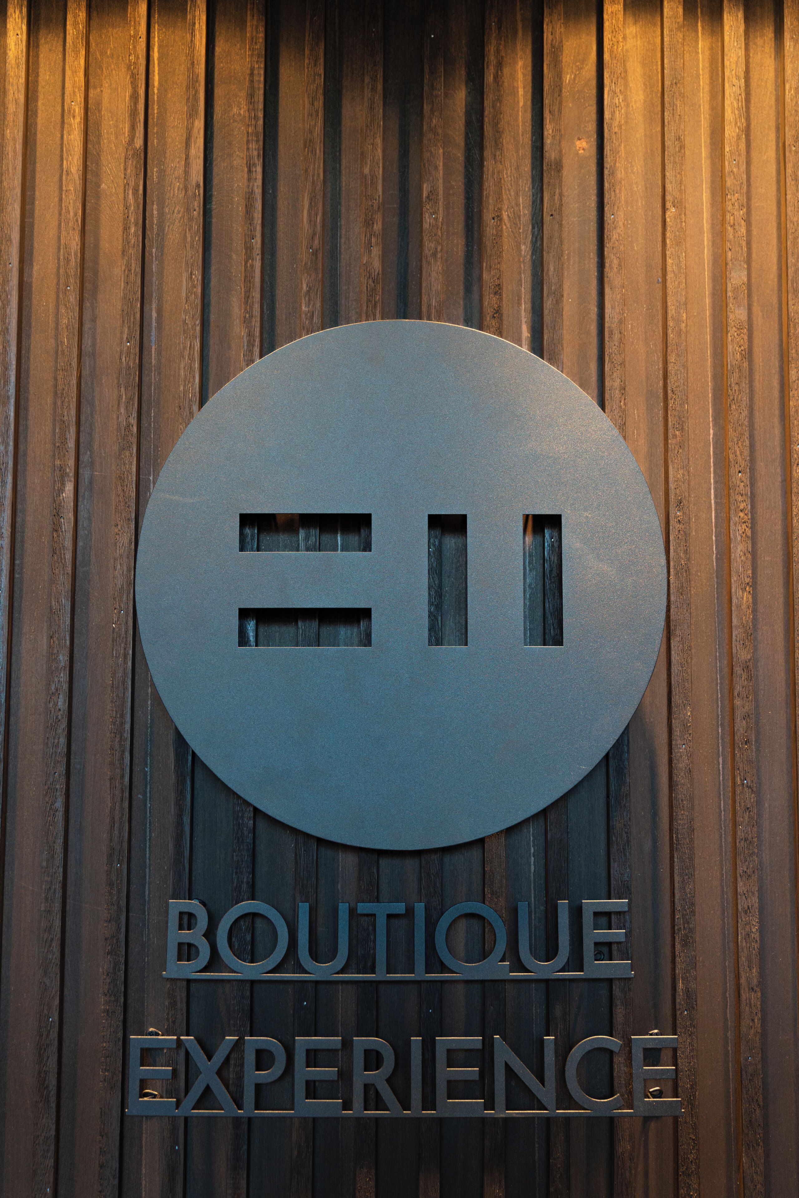 Een rond bord met de tekst 'BOUTIQUE EXPERIENCE' op een houten achtergrond.